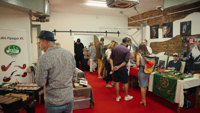 Tágas kiállítóterem tele látogatókkal és kiállítói asztalokkal